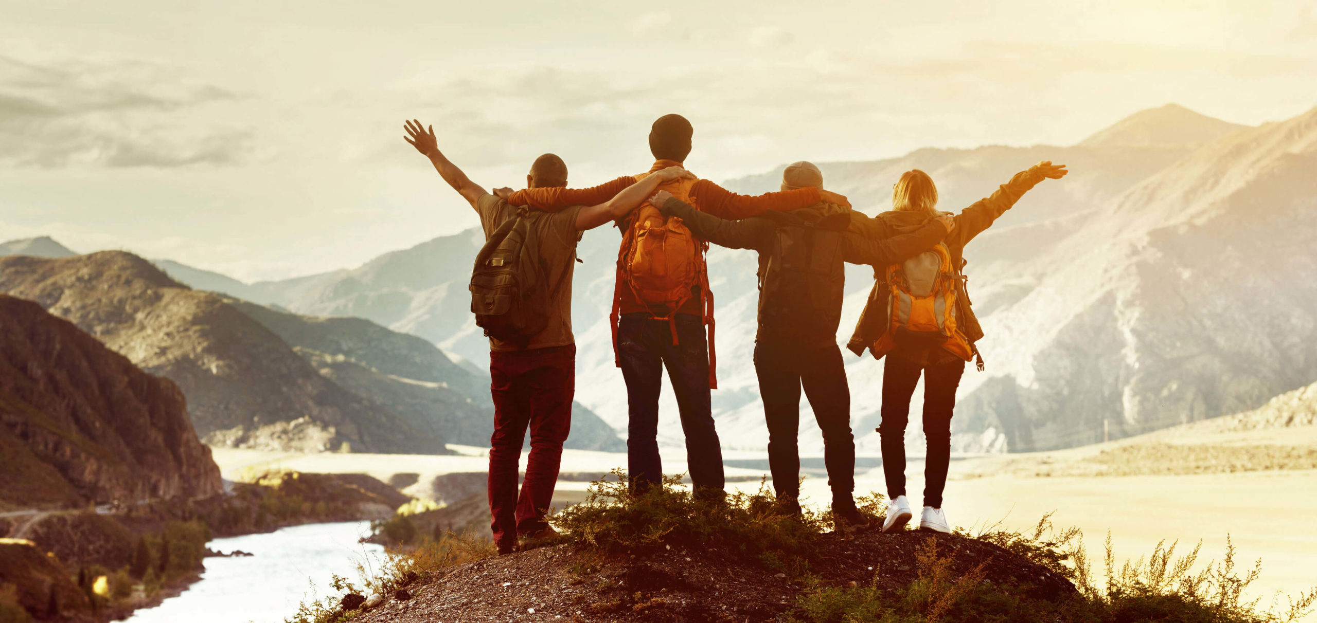 Group of people at top of mountain with arms raised